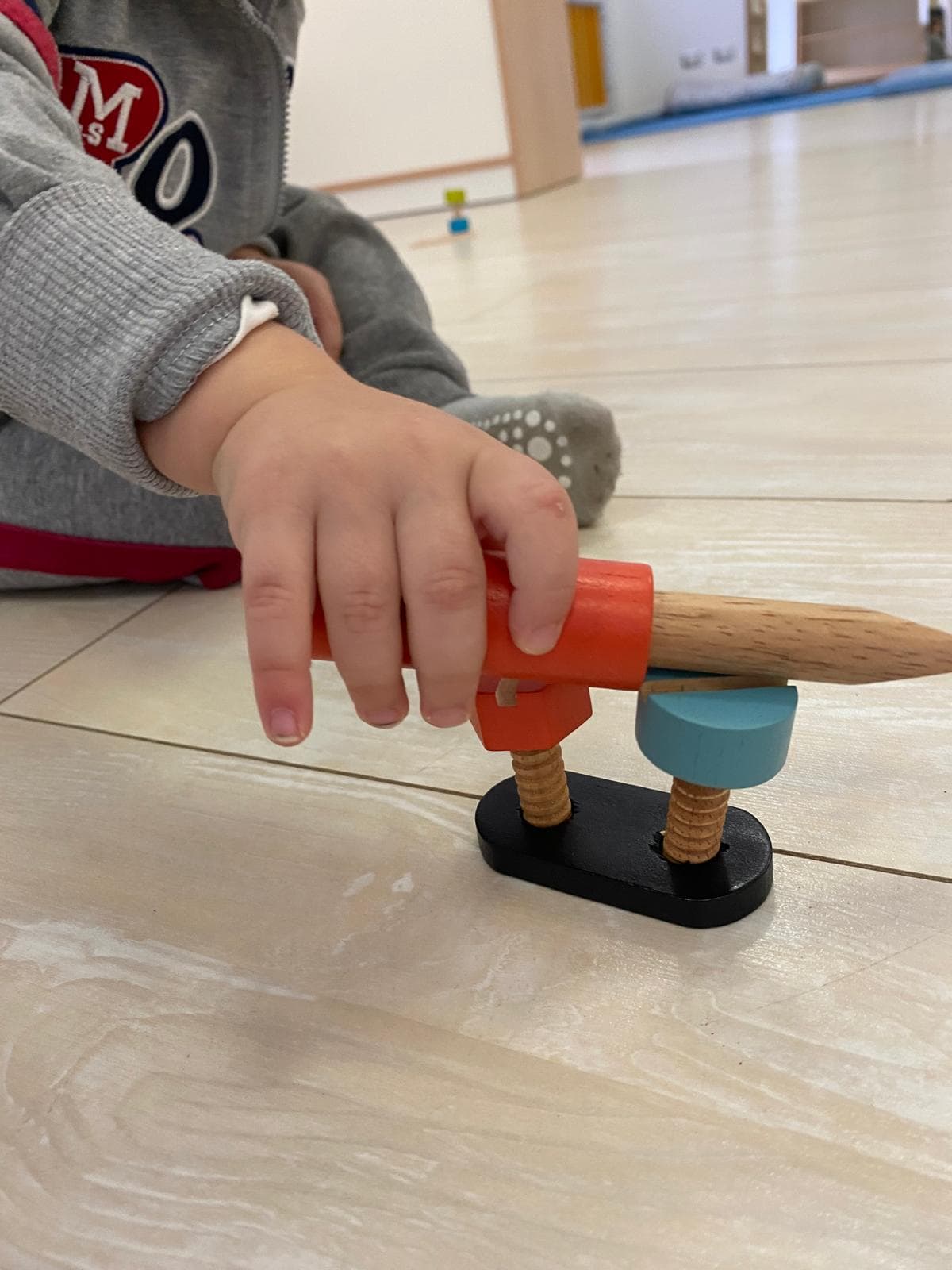 Bambina con viti e bulloni su piattini verdi